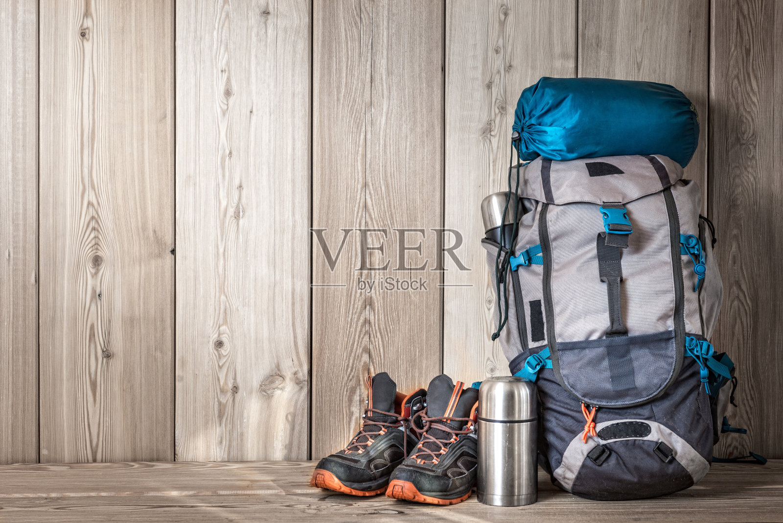 露营装备，鞋子，背包和一个保温瓶，木质背景照片摄影图片