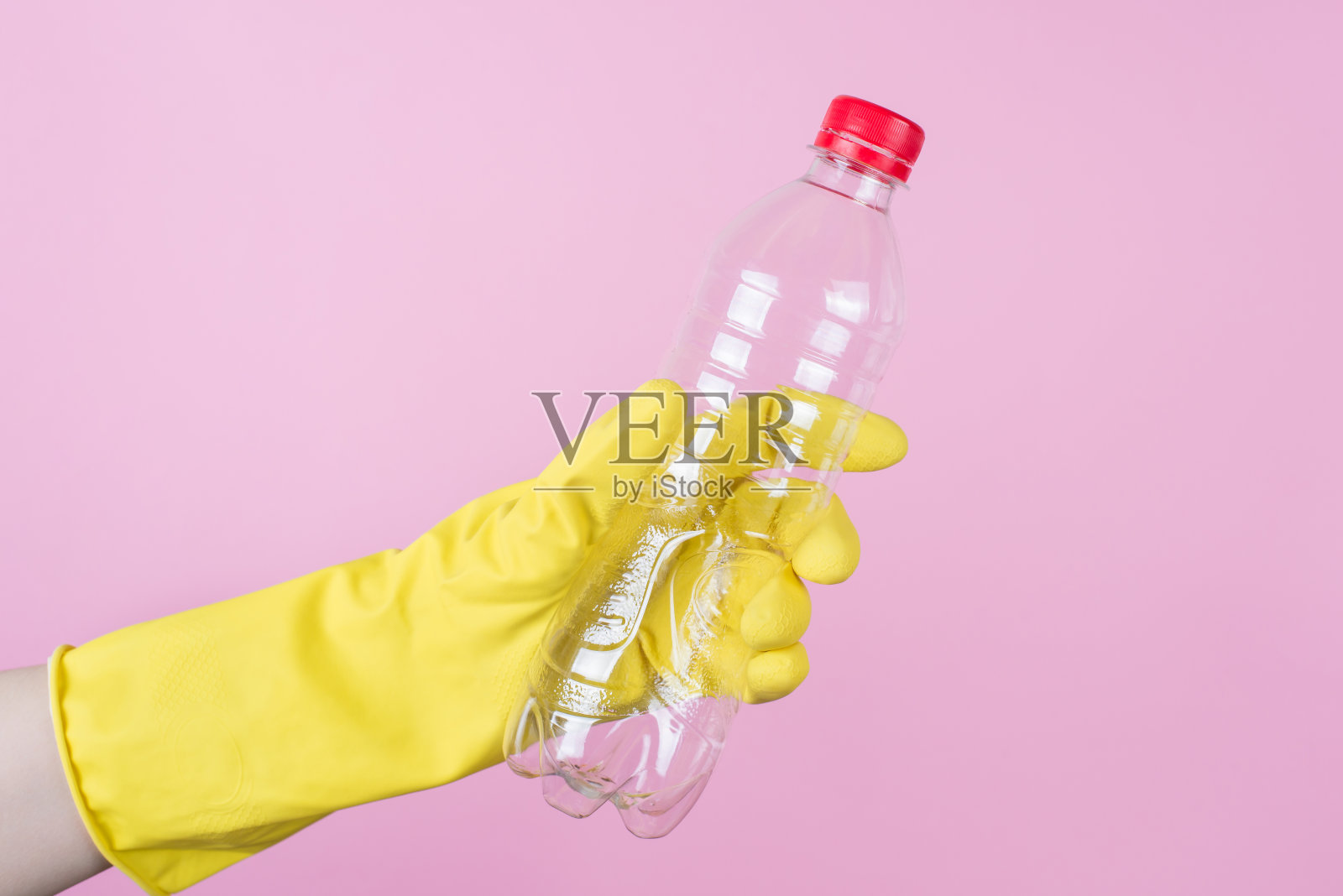 塑料回收的概念。裁剪近的侧面侧面视图照片的手在黄色手套持有一个空瓶子孤立的背景照片摄影图片