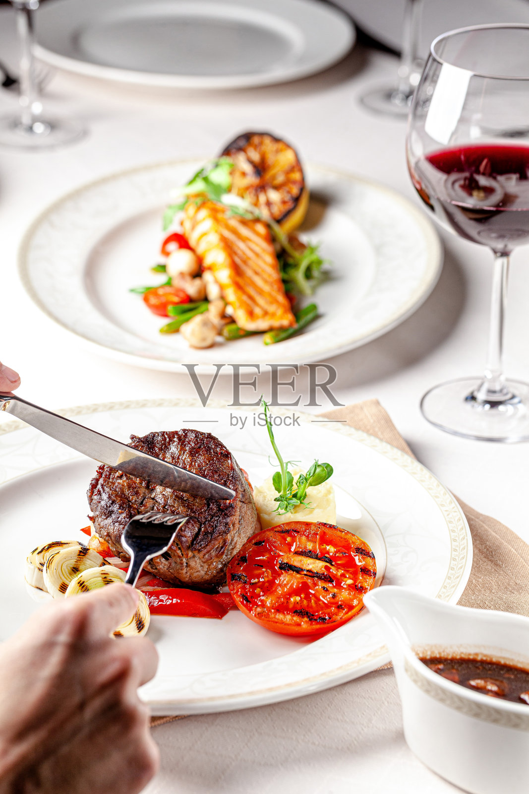 美国菜。一个男人在餐馆里吃着牛排和烤蔬菜，喝着红酒下肚。背景图像，复制空间文本照片摄影图片