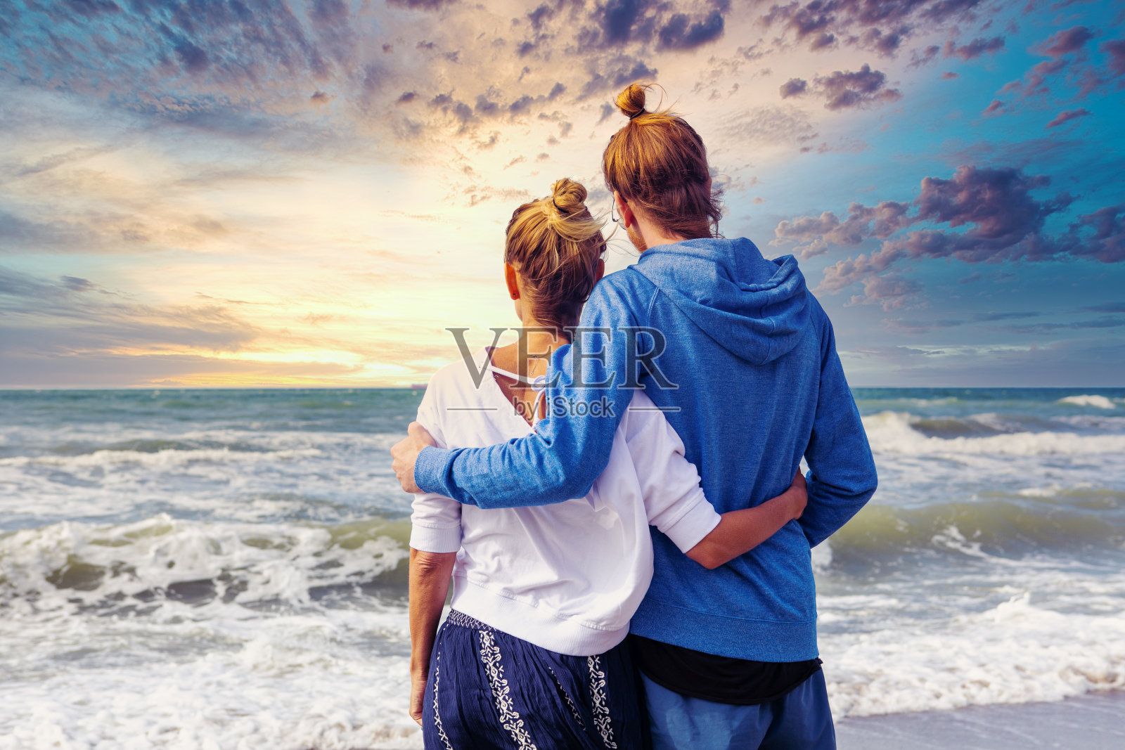 日落时分，一对年轻的情侣在海边拥抱照片摄影图片