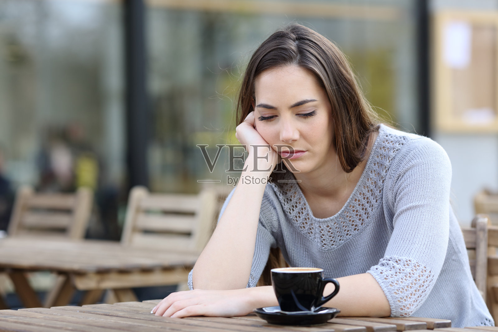 悲伤的女孩向下看着咖啡厅的露台，陷入沉思照片摄影图片