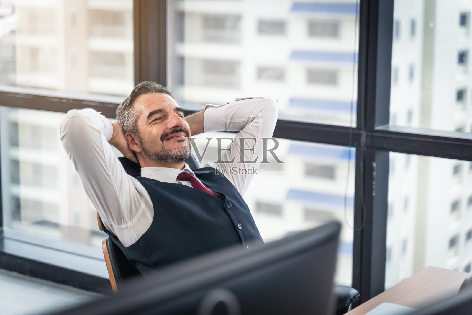 快乐的年轻商人工作在现代办公室轻松的椅子上，生活方式下班后在办公室坐着双手后面的快乐商人的人照片摄影图片