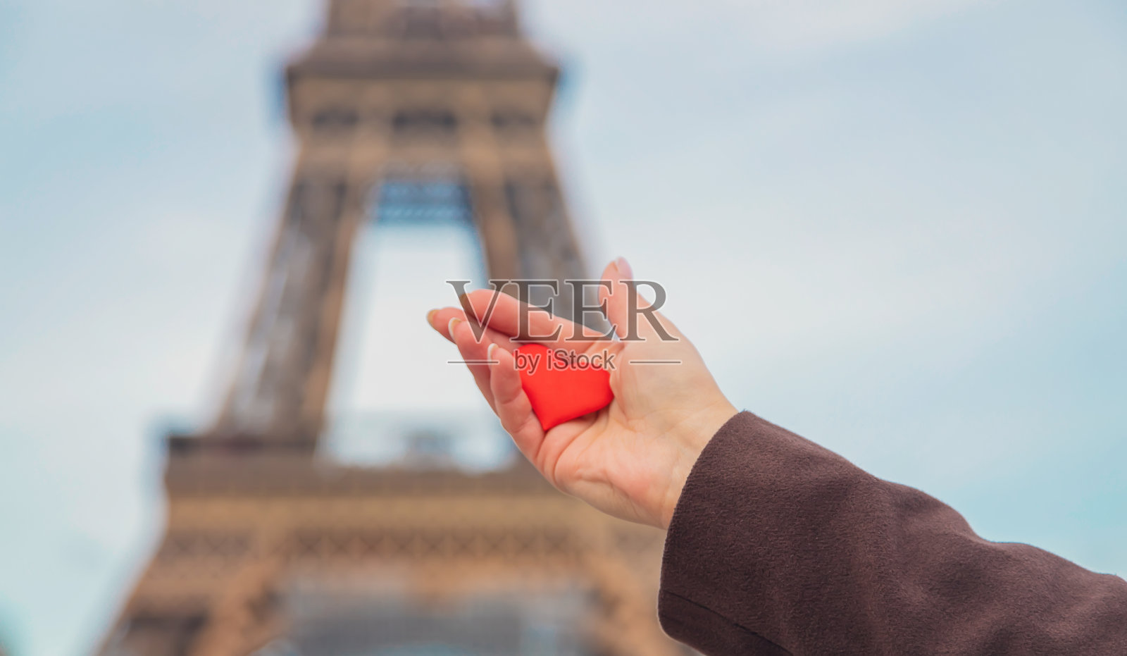 在巴黎埃菲尔铁塔附近，手捧心形。有选择性的重点。照片摄影图片