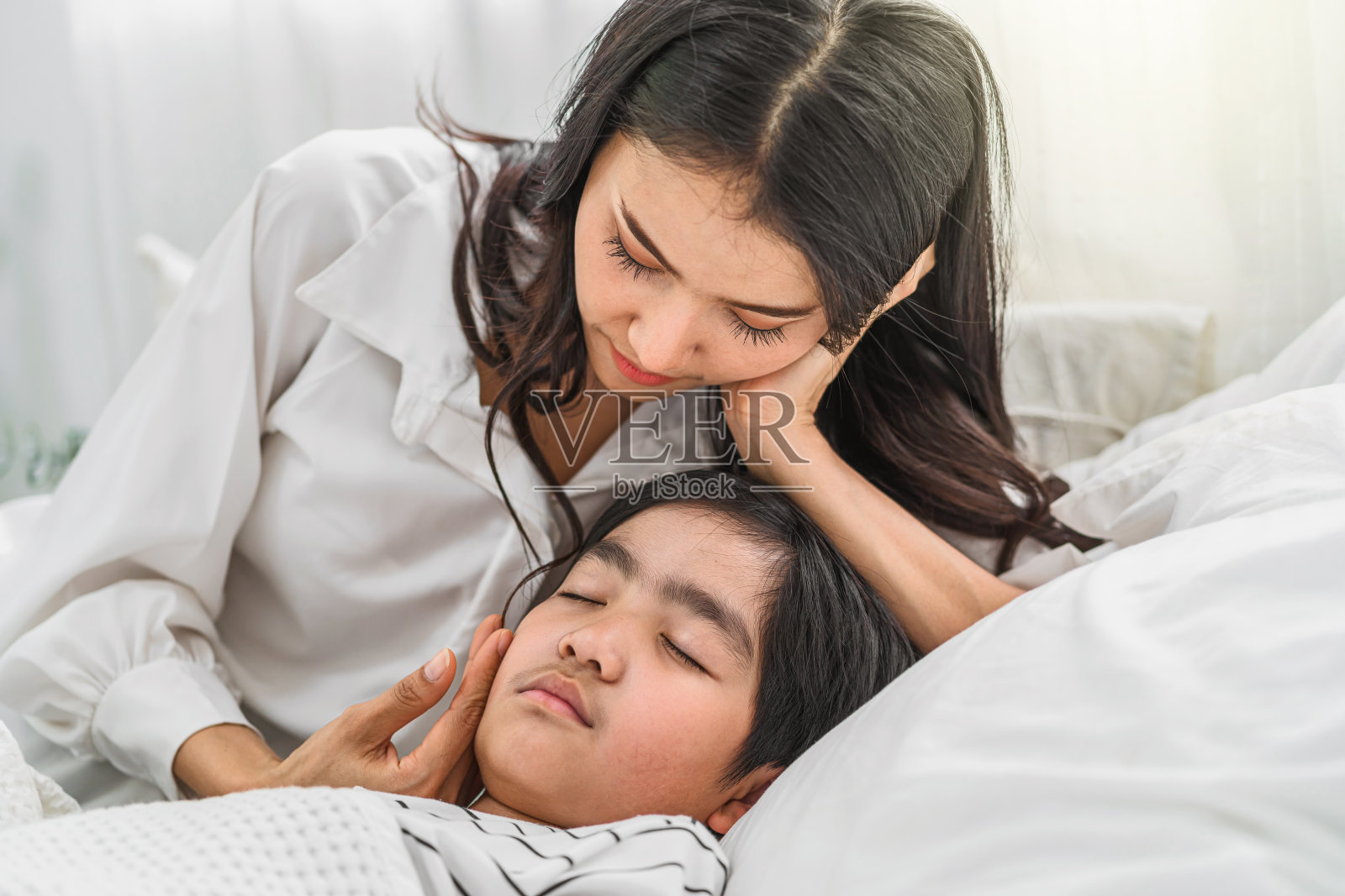 年轻的亚洲母亲照顾和检查儿子生病在床上照片摄影图片