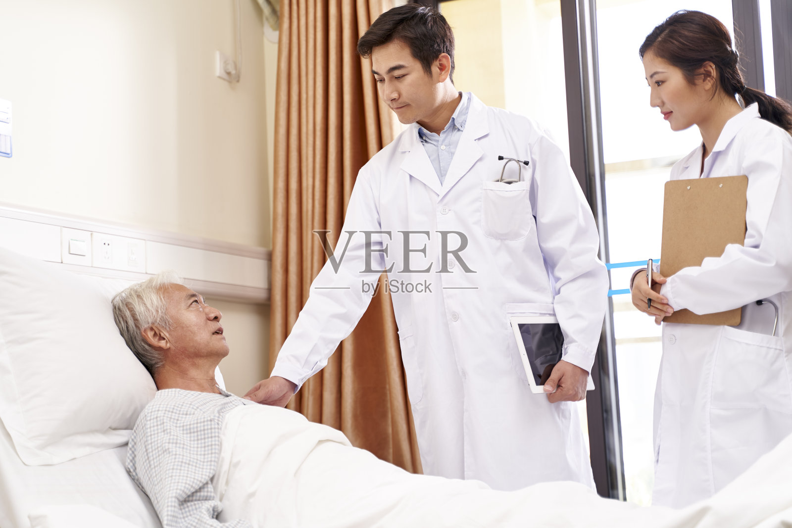 年轻的亚洲医生在医院检查老病人照片摄影图片