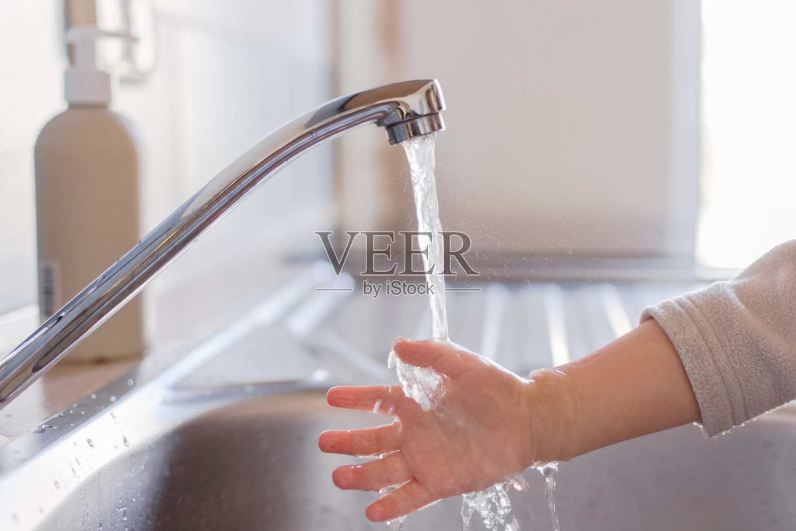 幼儿用肥皂和水洗手时，请紧抓双手。清洁卫生理念。照片摄影图片
