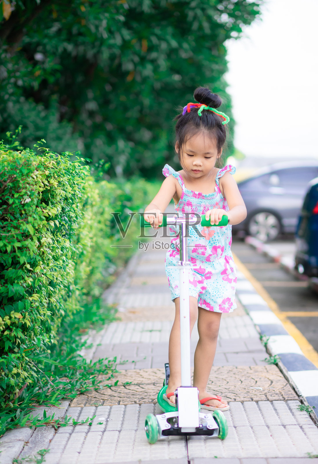 可爱的亚洲小女孩在人行道上学习骑摩托车照片摄影图片