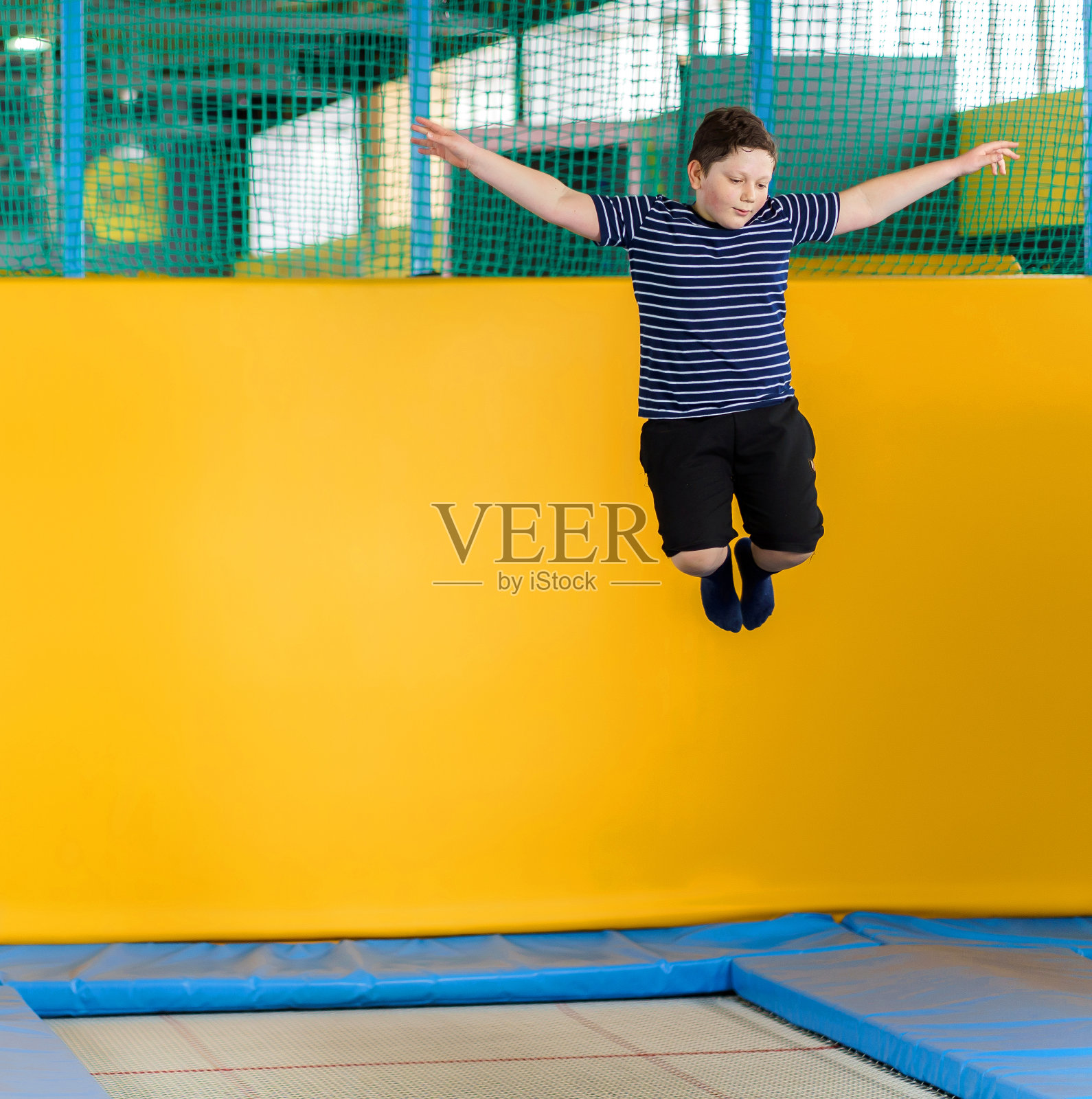 一个超重的可爱小男孩在儿童运动中心的室内蹦床上跳照片摄影图片