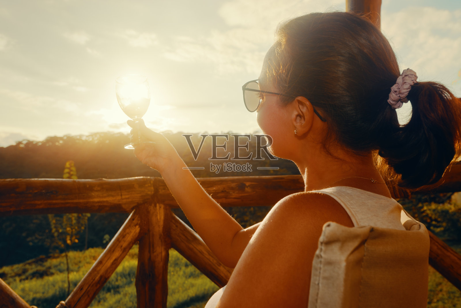戴着眼镜的年轻女子在日落时分的露台上休息照片摄影图片
