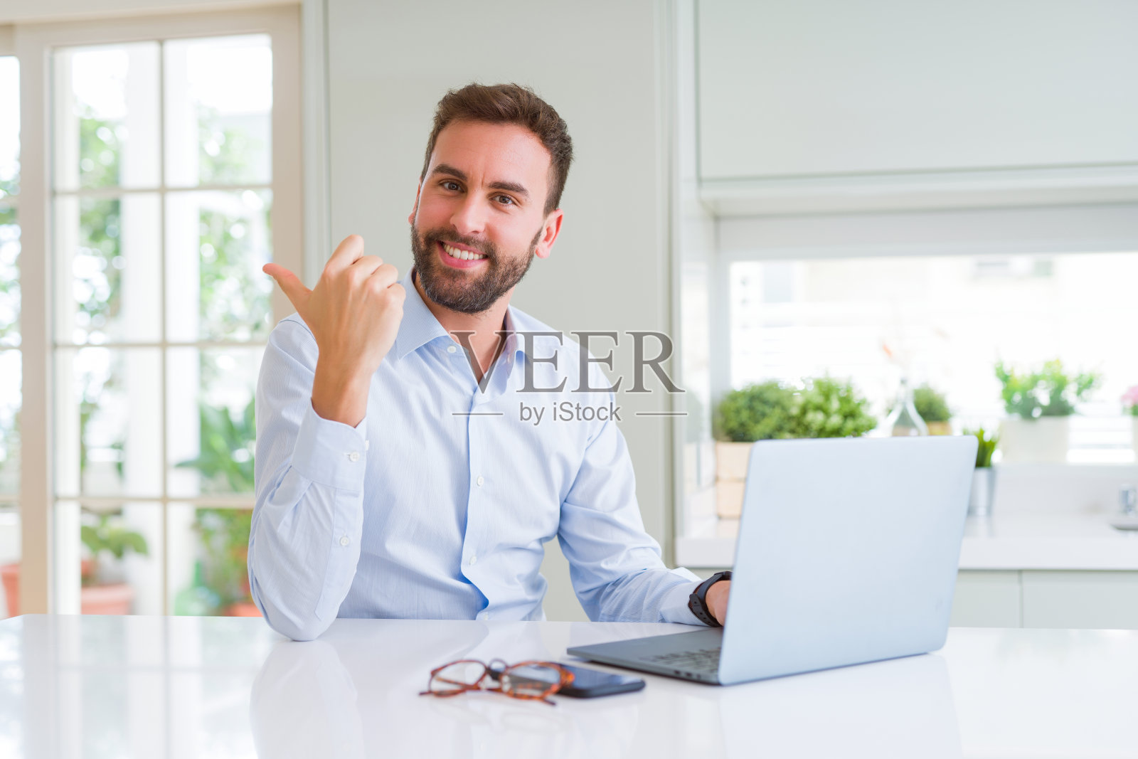 英俊的商人工作用电脑笔记本电脑指向和显示与拇指向上的一边与快乐的脸微笑照片摄影图片
