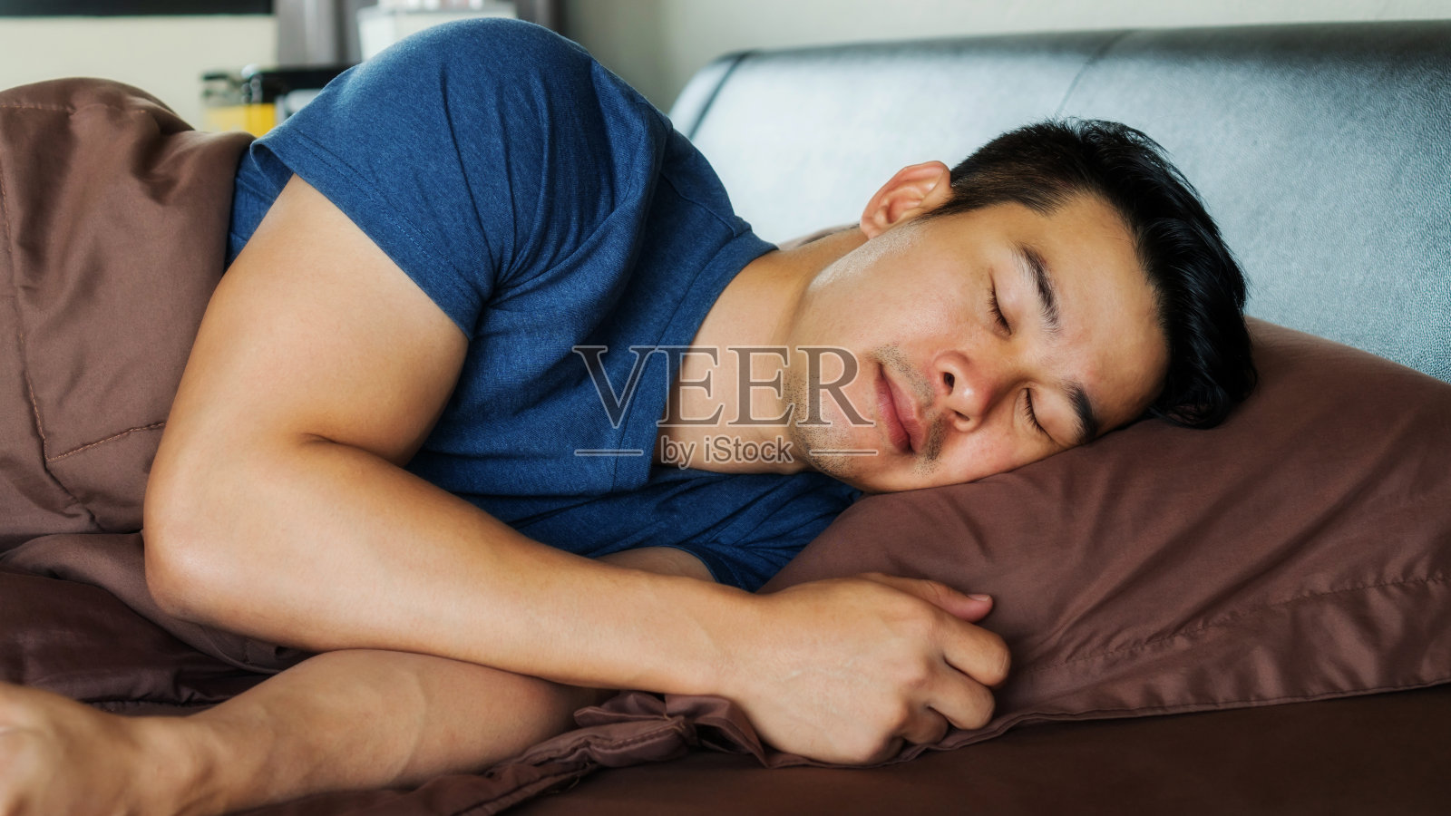 亚洲年轻人睡在一张棕色的床上。照片摄影图片