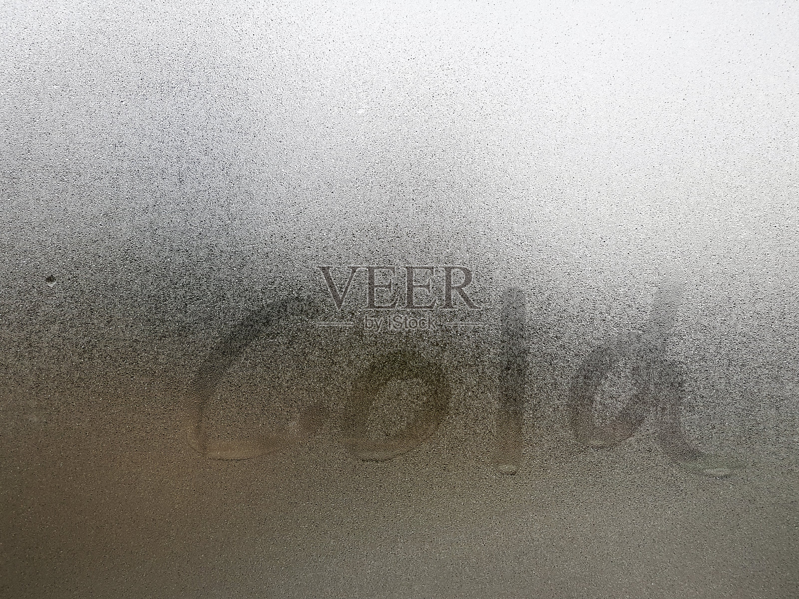 透明的玻璃上有雾和水滴在冬天，上面有冰冷的手写字母。特写自然美效果。背景和壁纸的概念。照片摄影图片