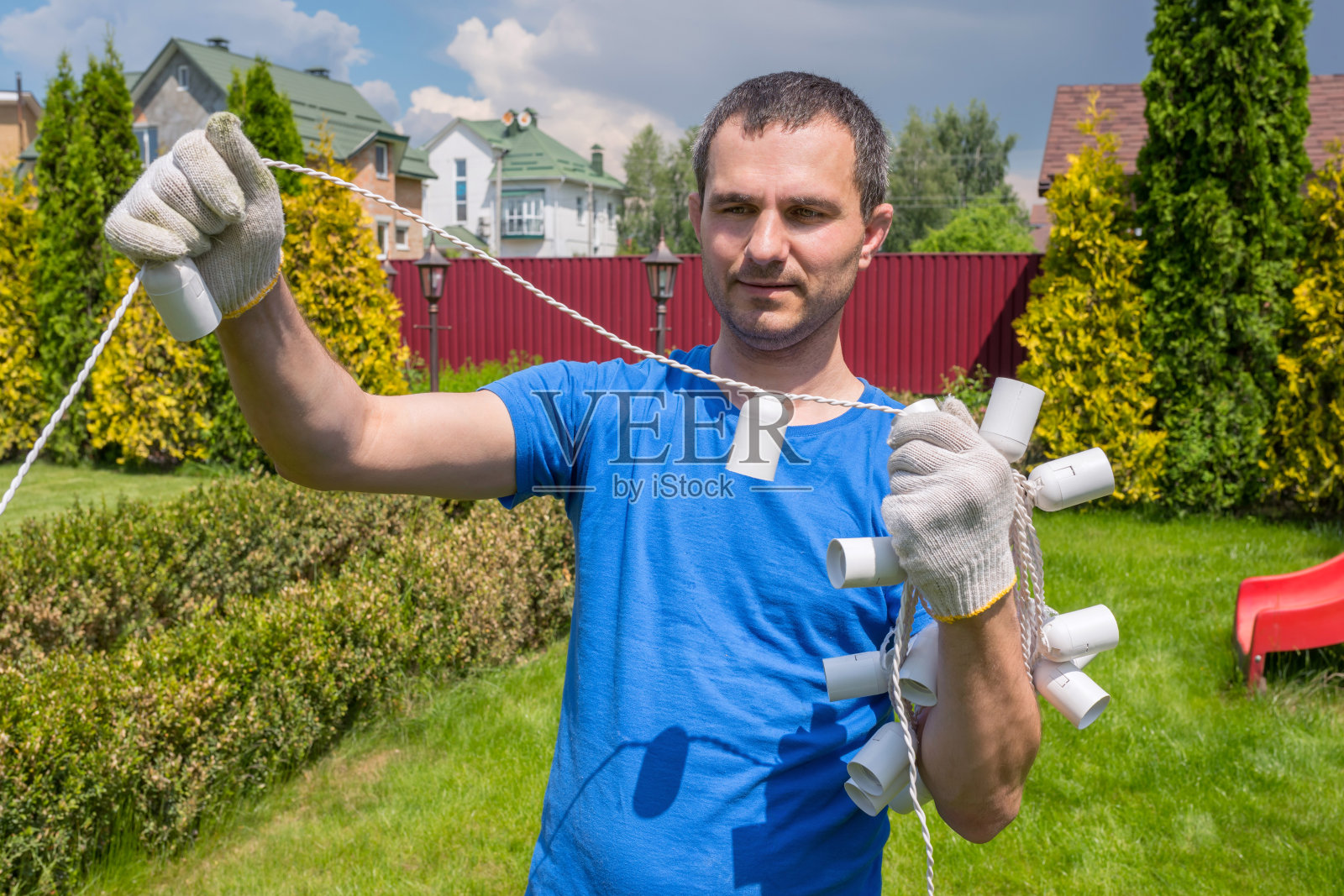 一个带着电缆的人在花园里工作。后院打扫。照片摄影图片