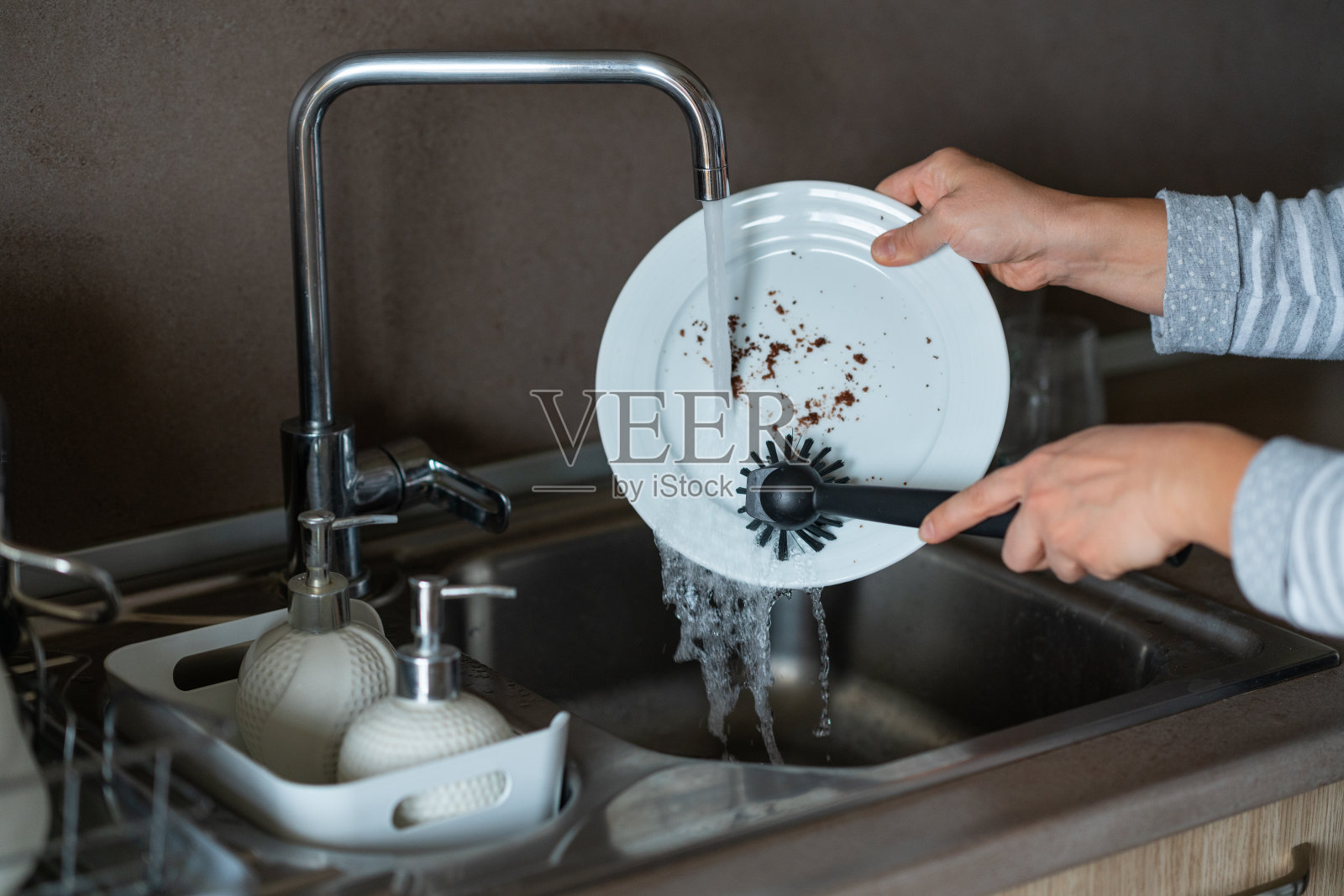 一个女人在厨房的水槽上手洗盘子照片摄影图片