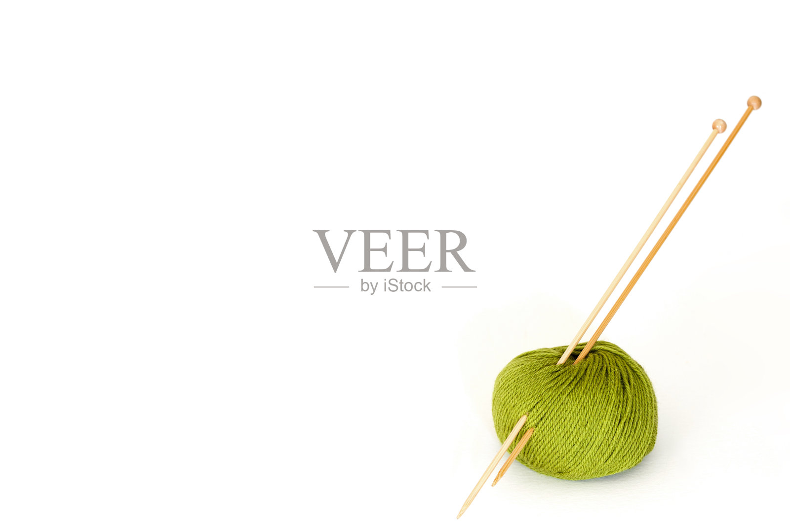 球绿色羊毛与竹编织针，白色背景与复制空间照片摄影图片