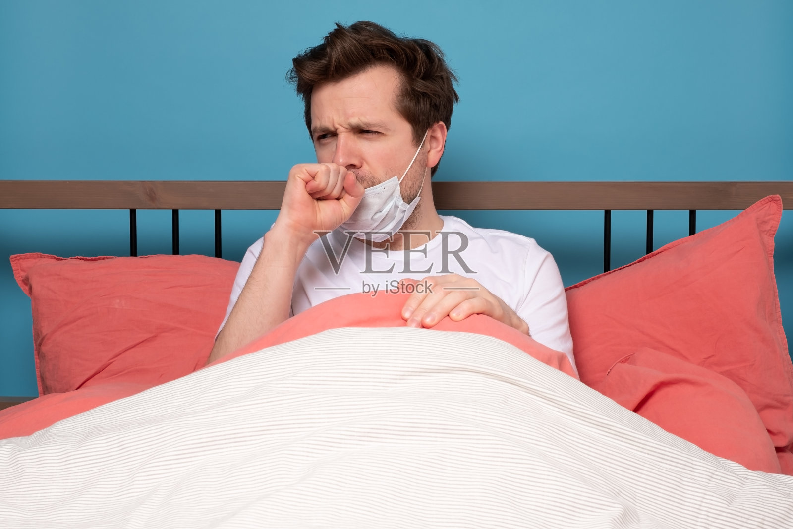 成熟的男人因为感冒独自坐在床上咳嗽。照片摄影图片