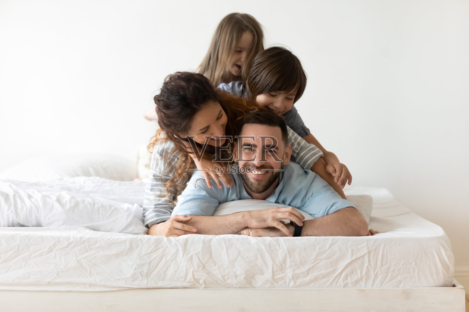 快乐的年轻家庭和孩子们在卧室放松照片摄影图片