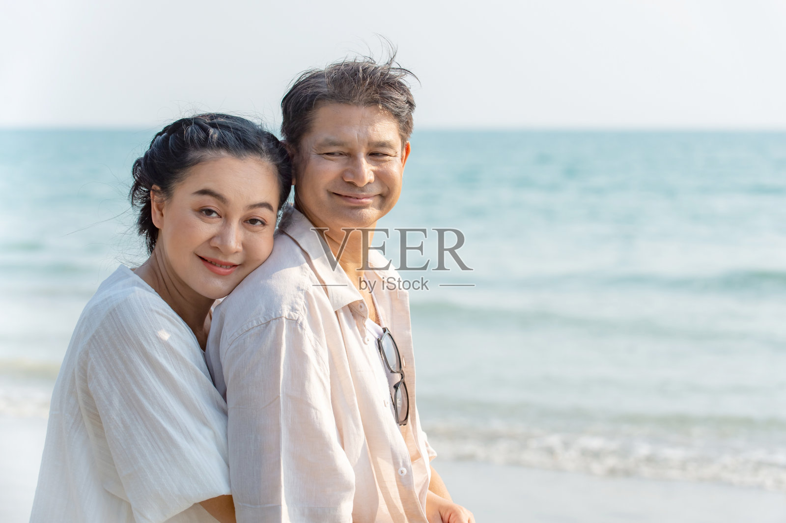 快乐的亚洲资深夫妇男女在热带海滩拥抱在一起，看着镜头与微笑的脸。退休养老家庭在浪漫的暑假度假旅行中放松照片摄影图片