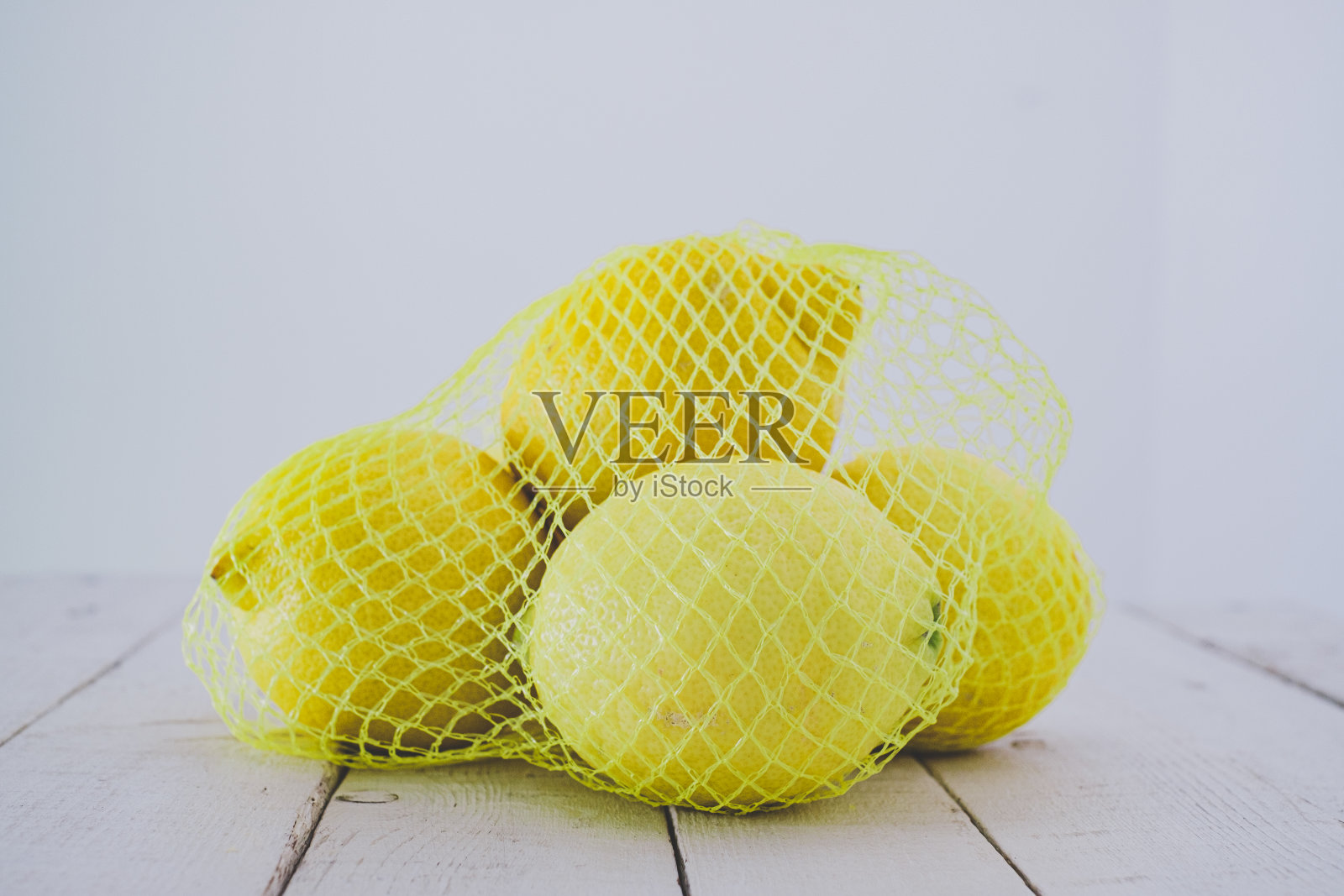 网眼袋里的新鲜柠檬。照片摄影图片