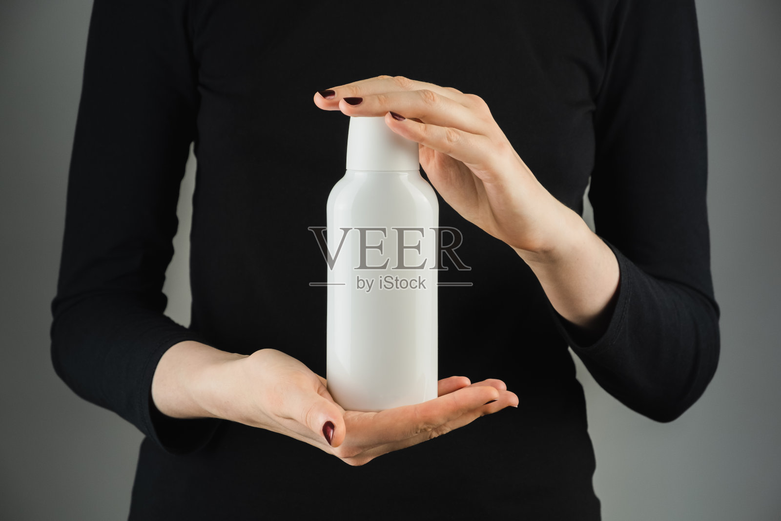在低光背景下，普通的白色瓶子在女性手中。照片摄影图片
