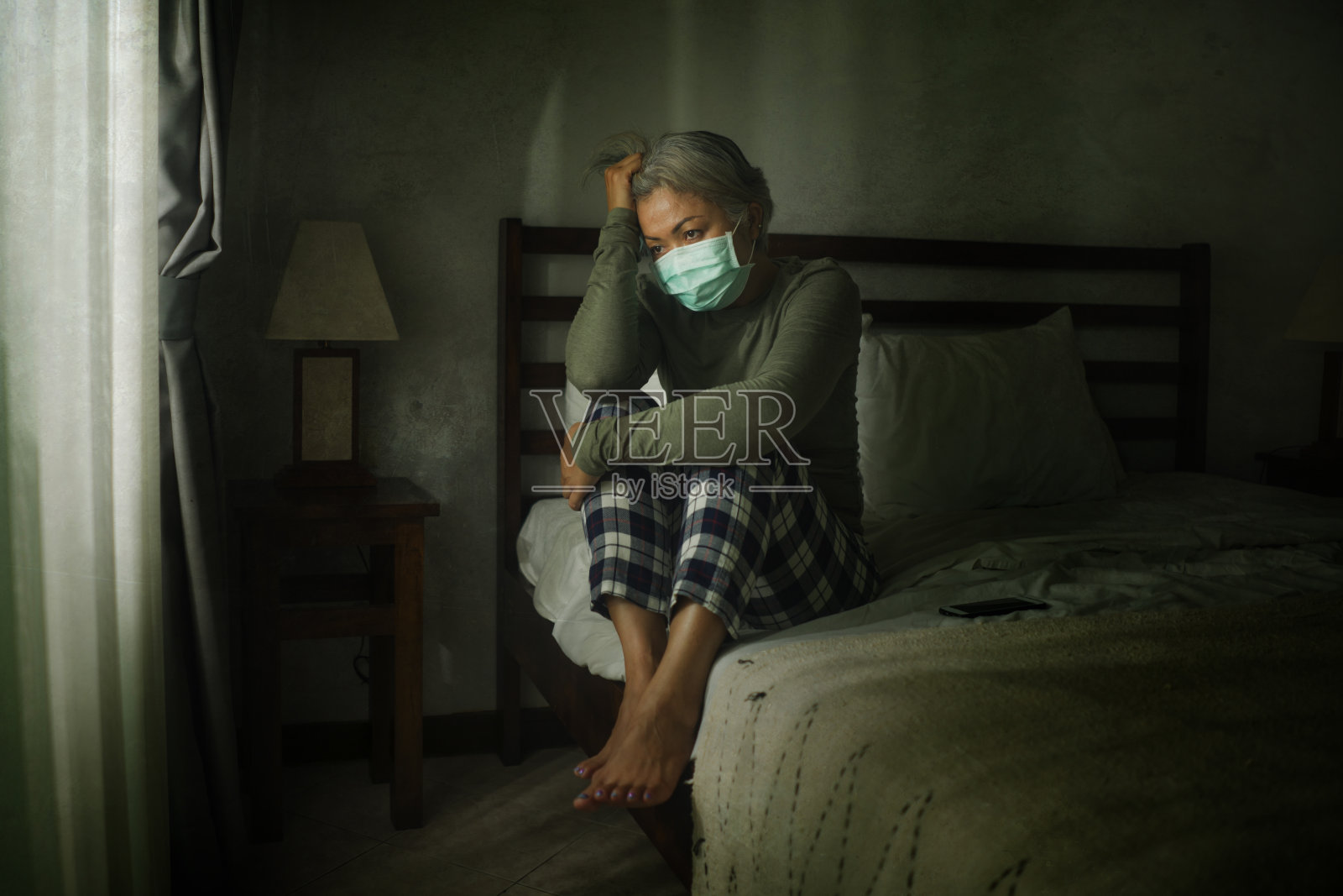 这是一幅生动的肖像，描绘的是在COVID-19病毒危机期间，一名50多岁、头发灰白、戴着防护面具的中年妇女，她在恐惧和压力中表现得非常谨慎照片摄影图片
