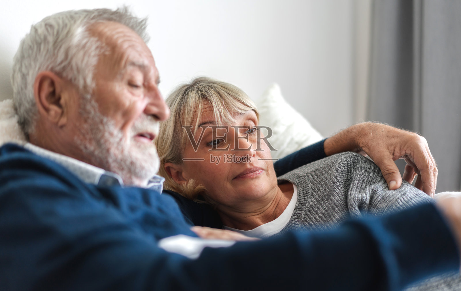 一对老年幸福夫妇躺在家里卧室的床上一起放松和交谈。退休夫妇的概念照片摄影图片