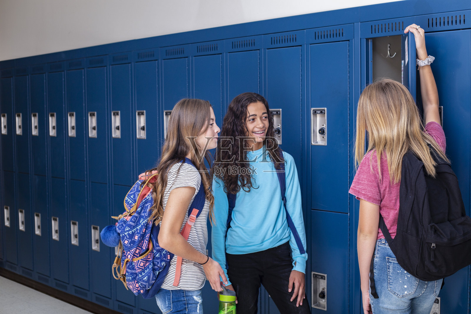 在学校走廊里，一群初中生站在储物柜旁聊天照片摄影图片