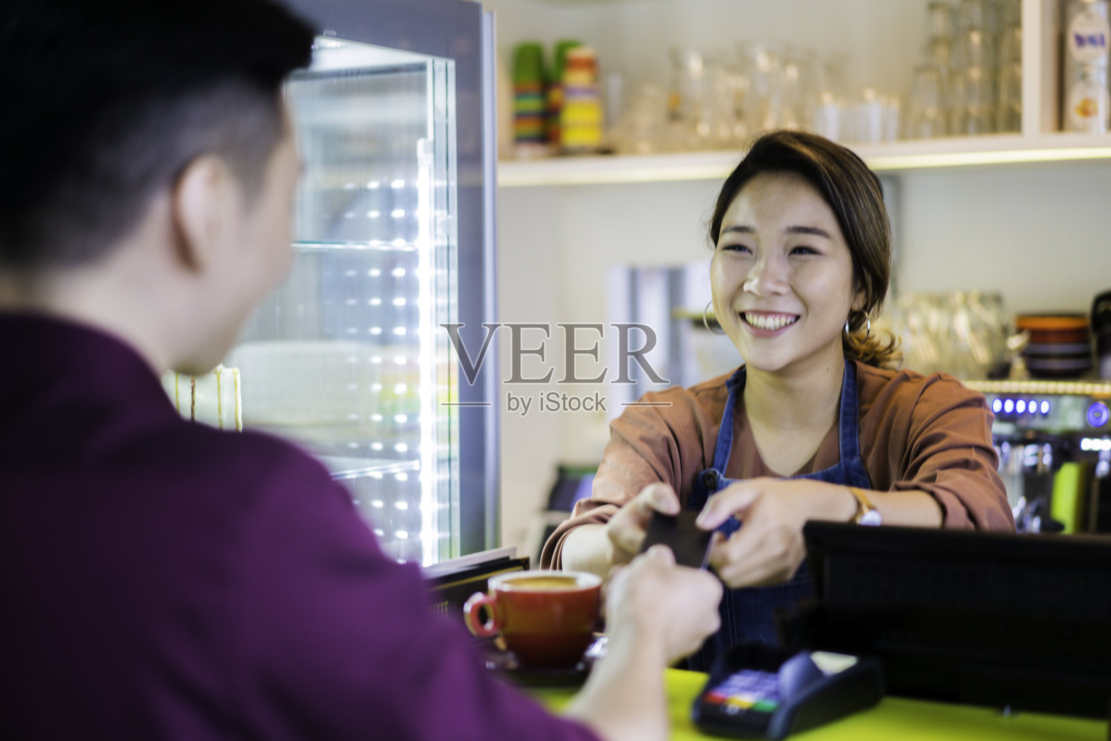 美丽的亚洲女招待收到信用卡无线支付客户在café。照片摄影图片