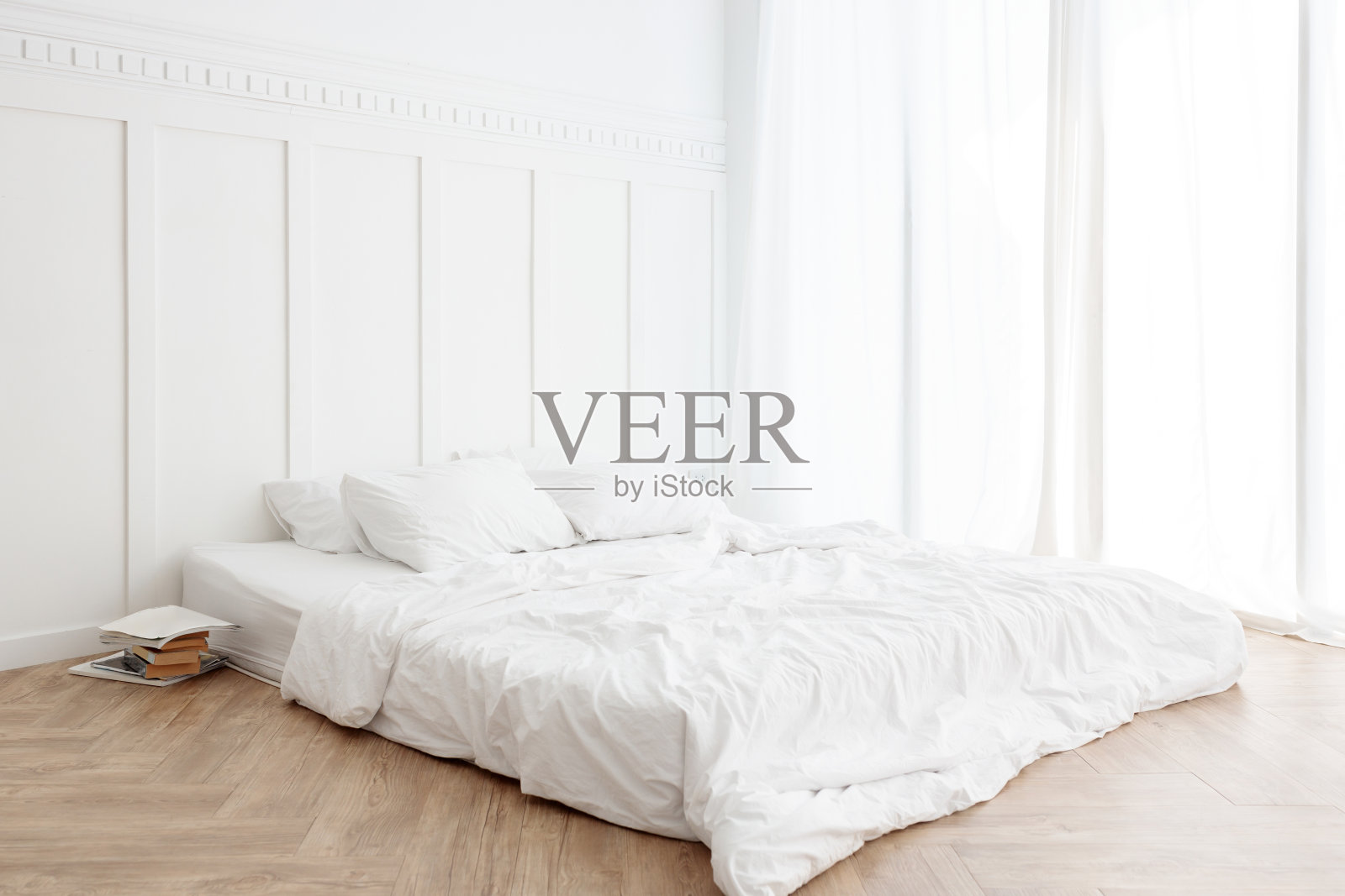 室内视图，未整理的凌乱的床在一个早晨的木地板上，有窗帘和阳光照片摄影图片