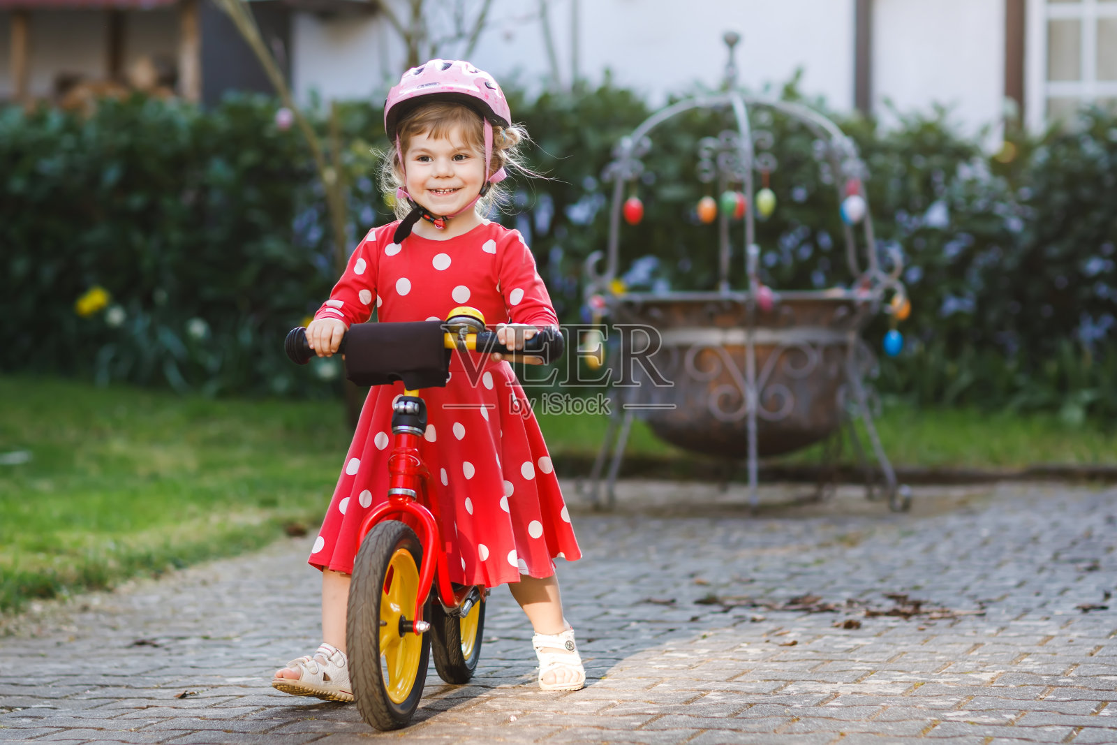 可爱的小女孩戴着安全帽骑在跑步平衡自行车上。快乐，健康，可爱的婴儿，孩子有乐趣的学习在更瘦的自行车劳福瑞德。阳光明媚温暖的一天，活泼的孩子在户外。照片摄影图片