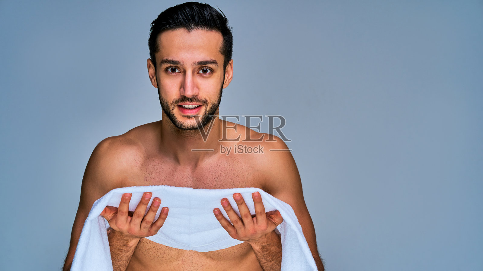一个黑发胡子男手里拿着一条打开的白毛巾。美丽的概念照片摄影图片