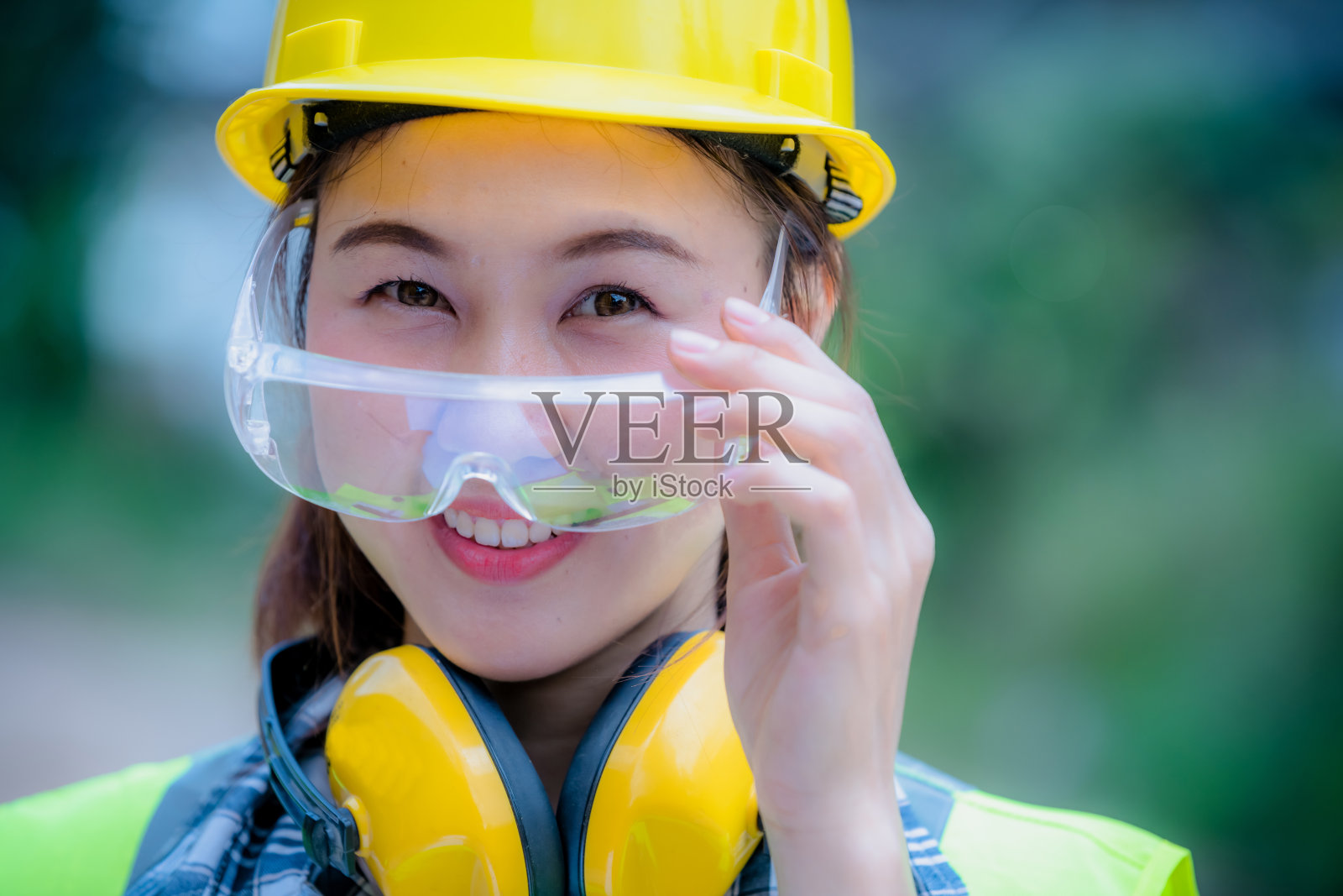 图为工业女工穿着工作服，微笑着站在工业工厂控制操作机器上工作。照片摄影图片