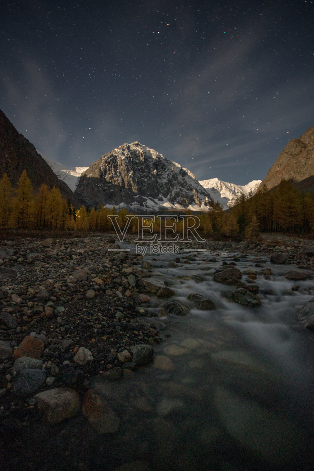在白雪皑皑的山峰和星空的映衬下，长时间曝光河流和石头。美丽的照片照片摄影图片