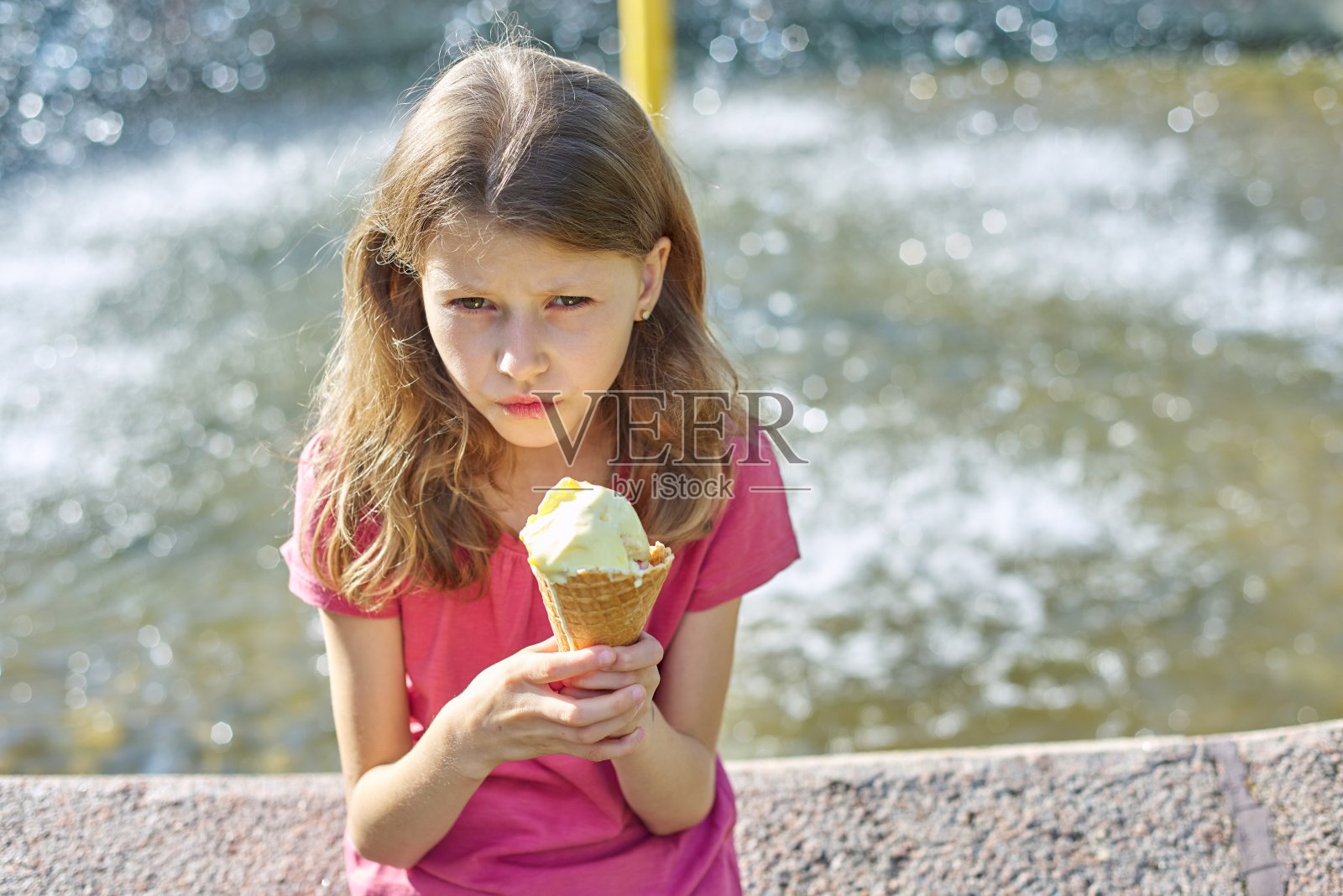 伤心的小女孩手里拿着冰淇淋，夏天公园的背景照片摄影图片
