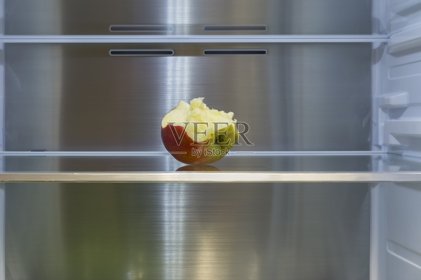 空冰箱里有一个被咬过的苹果。协助交付产品。照片摄影图片
