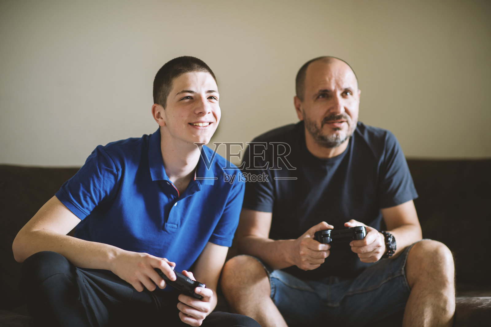 父亲和儿子在家里一起玩电子游戏照片摄影图片