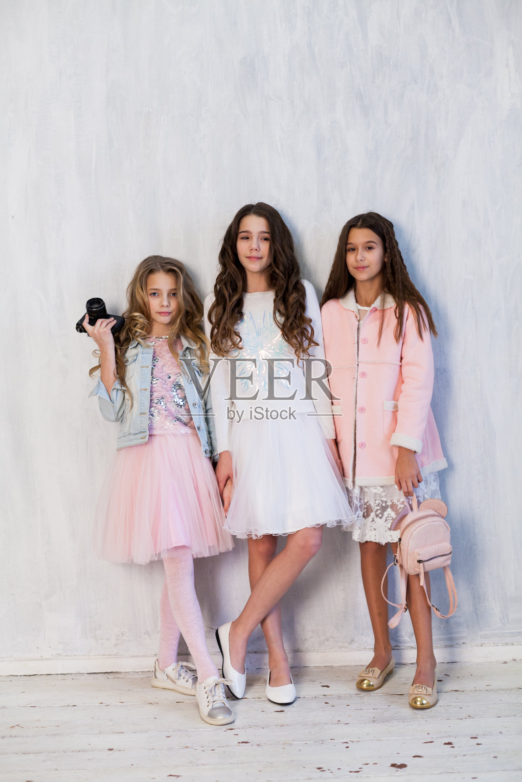 三个漂亮时髦的女孩，她的女朋友都穿着粉红色的白裙子照片摄影图片