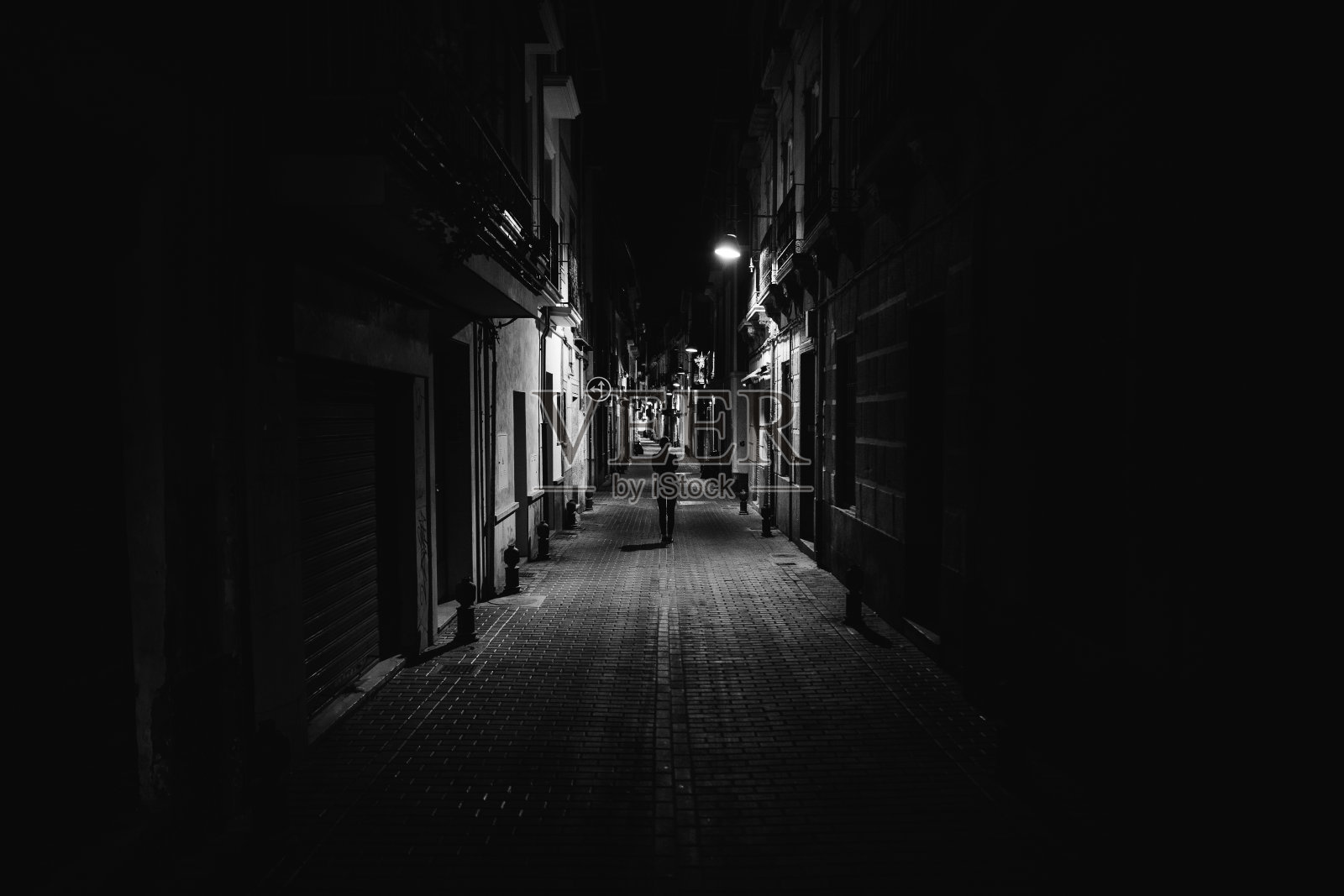 深夜独自走在街上的女人。狭窄黑暗的小巷，不安全的女性剪影。空荡荡的街道上。女人独自步行。警察小时。殴打情况，对妇女的暴力观念。照片摄影图片