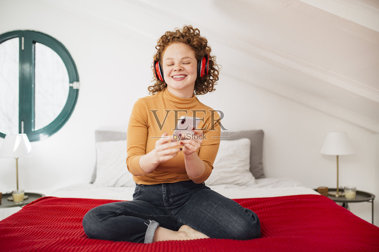 快乐的年轻红发女人享受着智能手机上的音乐照片摄影图片