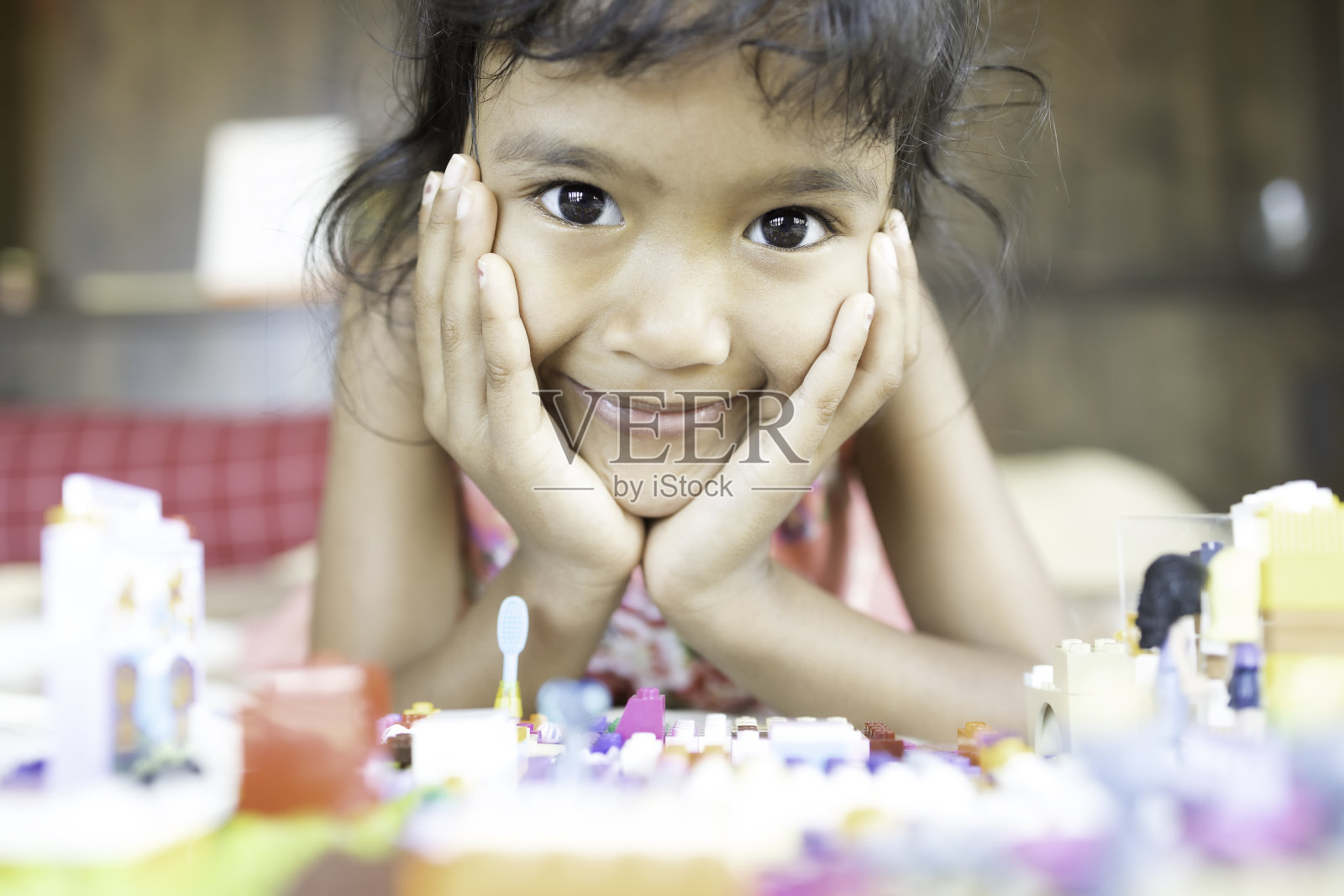 一个亚洲女孩正在卧室的床上玩一块塑料砖。照片摄影图片