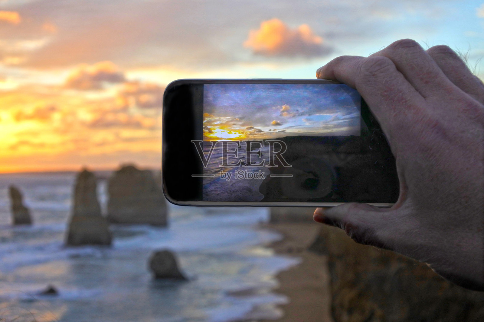 一个成年人的手在度假用手机拍照的风景十二使徒照片摄影图片