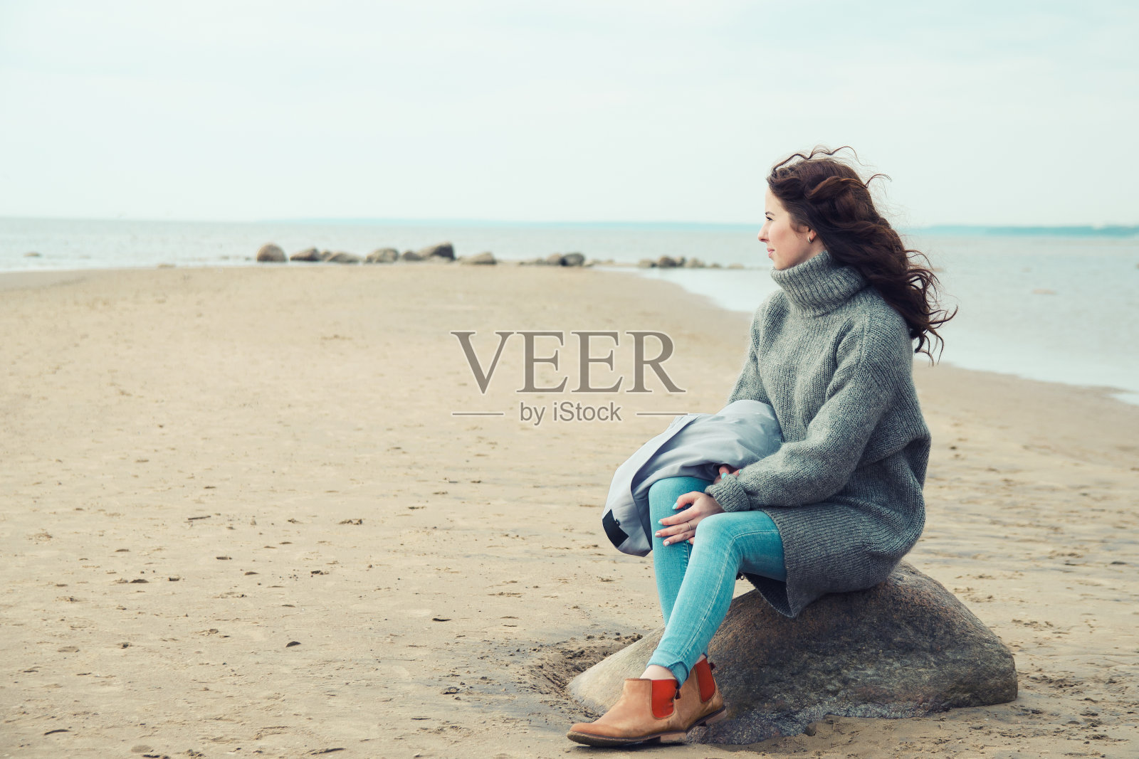 有魅力的女人穿着暖和的羊毛衫在寒冷的海滩上照片摄影图片