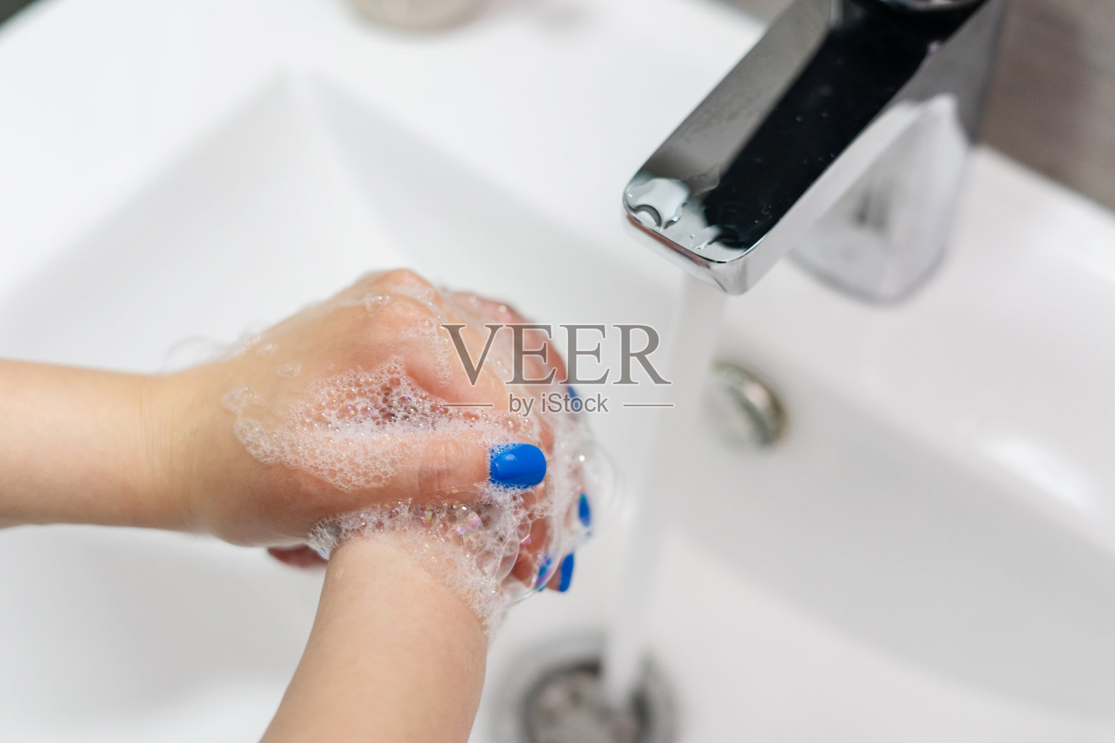 近距离观察不明白种人女性用肥皂泡沫在浴室水槽、水龙头、水龙头洗手，以清洁和消毒预防疾病，在家里的天俯视图照片摄影图片