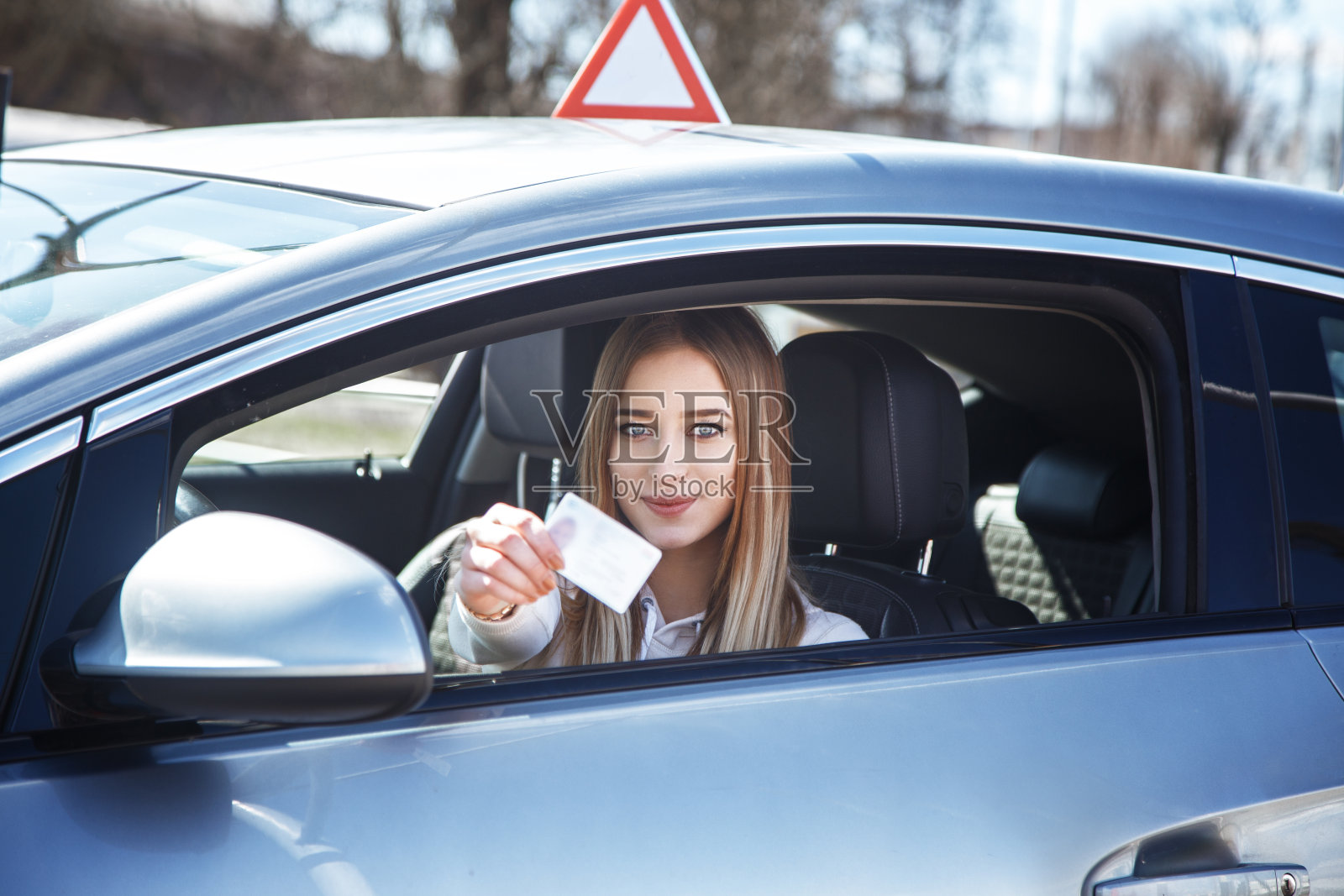快乐的女孩开着一辆训练车手里拿着驾照照片摄影图片