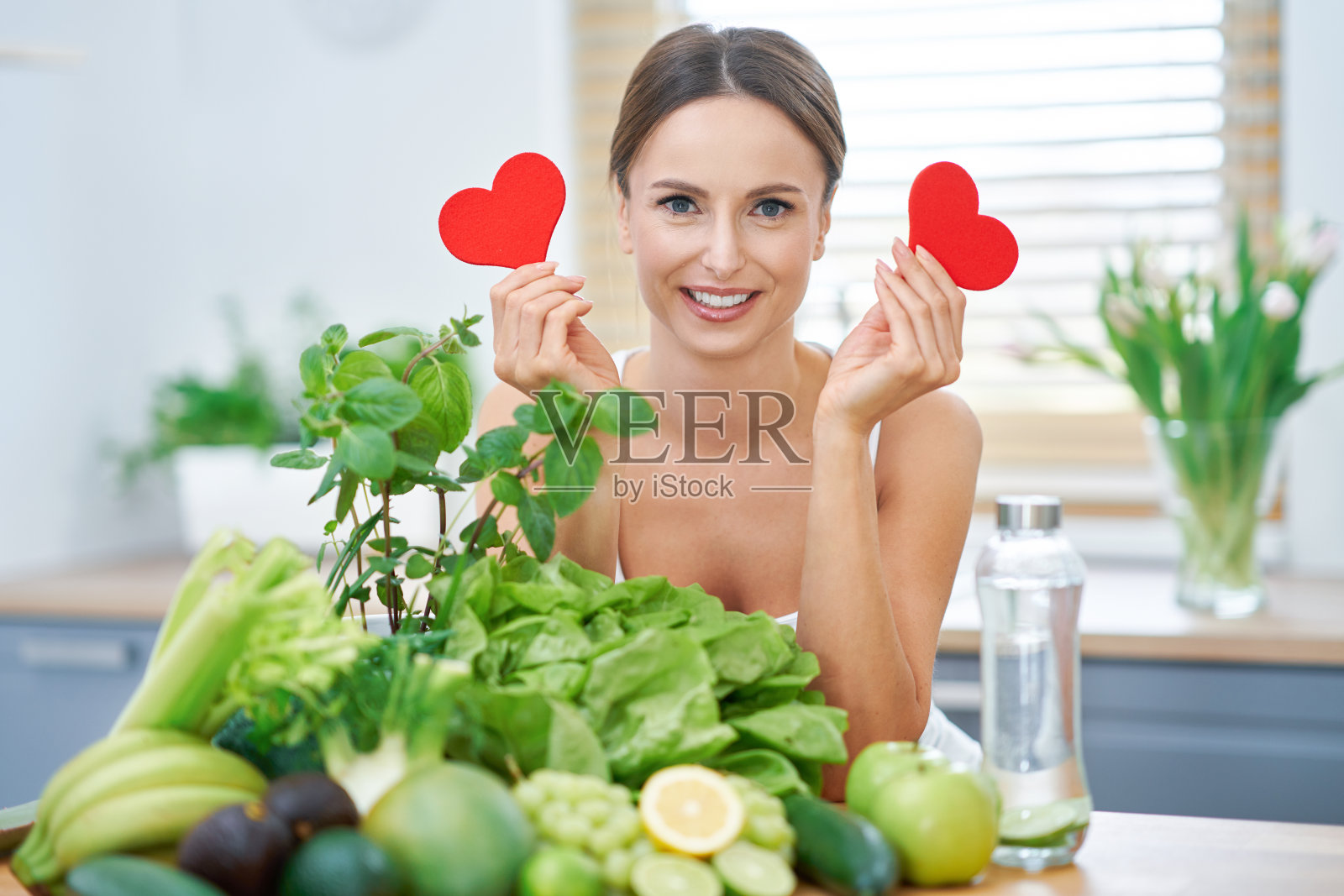健康的成年女性，厨房里有绿色食物照片摄影图片