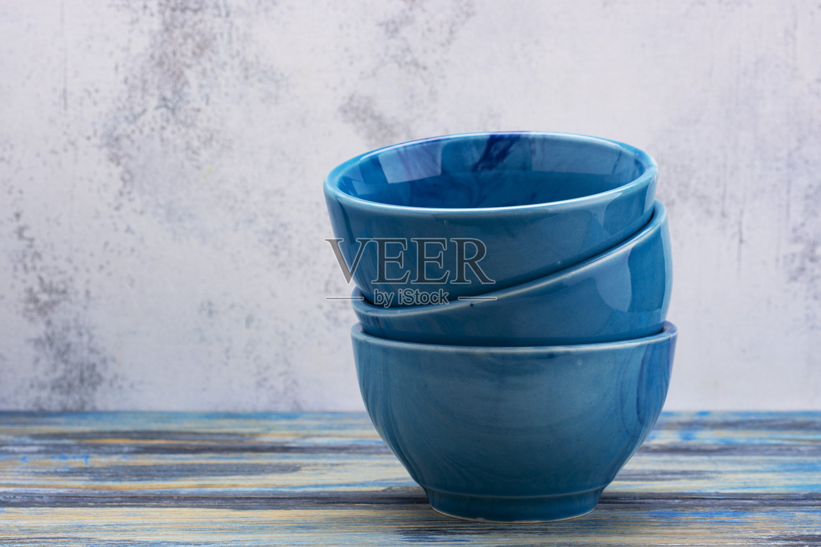木制背景上放着三个蓝色的空碗。照片摄影图片