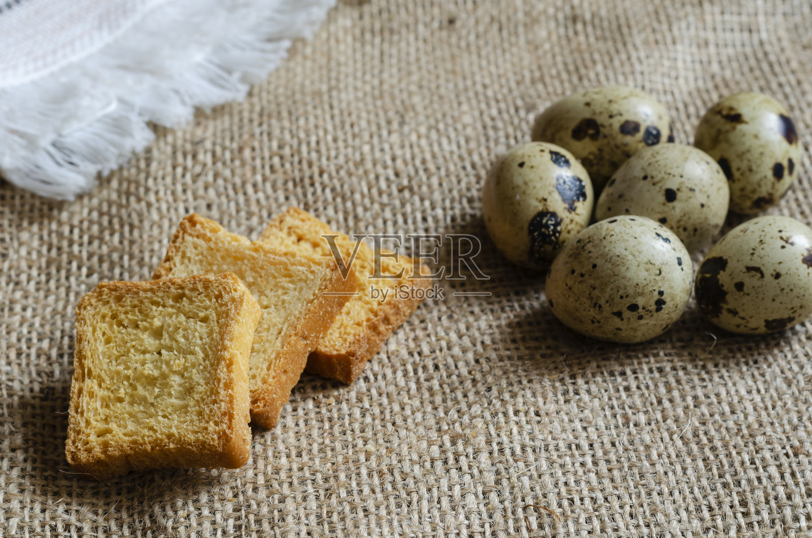 方形面包丁和生鹌鹑蛋放在粗麻布上。照片摄影图片