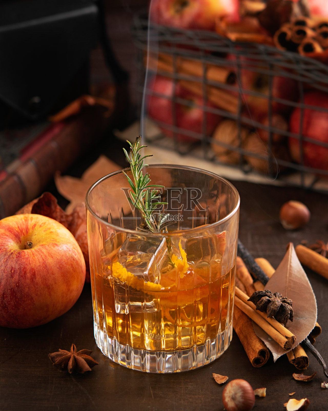 威士忌或波本威士忌加冰，迷迭香枝加烟和苹果，肉桂棒。神奇的秋季概念，轻松惬意的酒吧氛围。复制空间，选择焦点。照片摄影图片