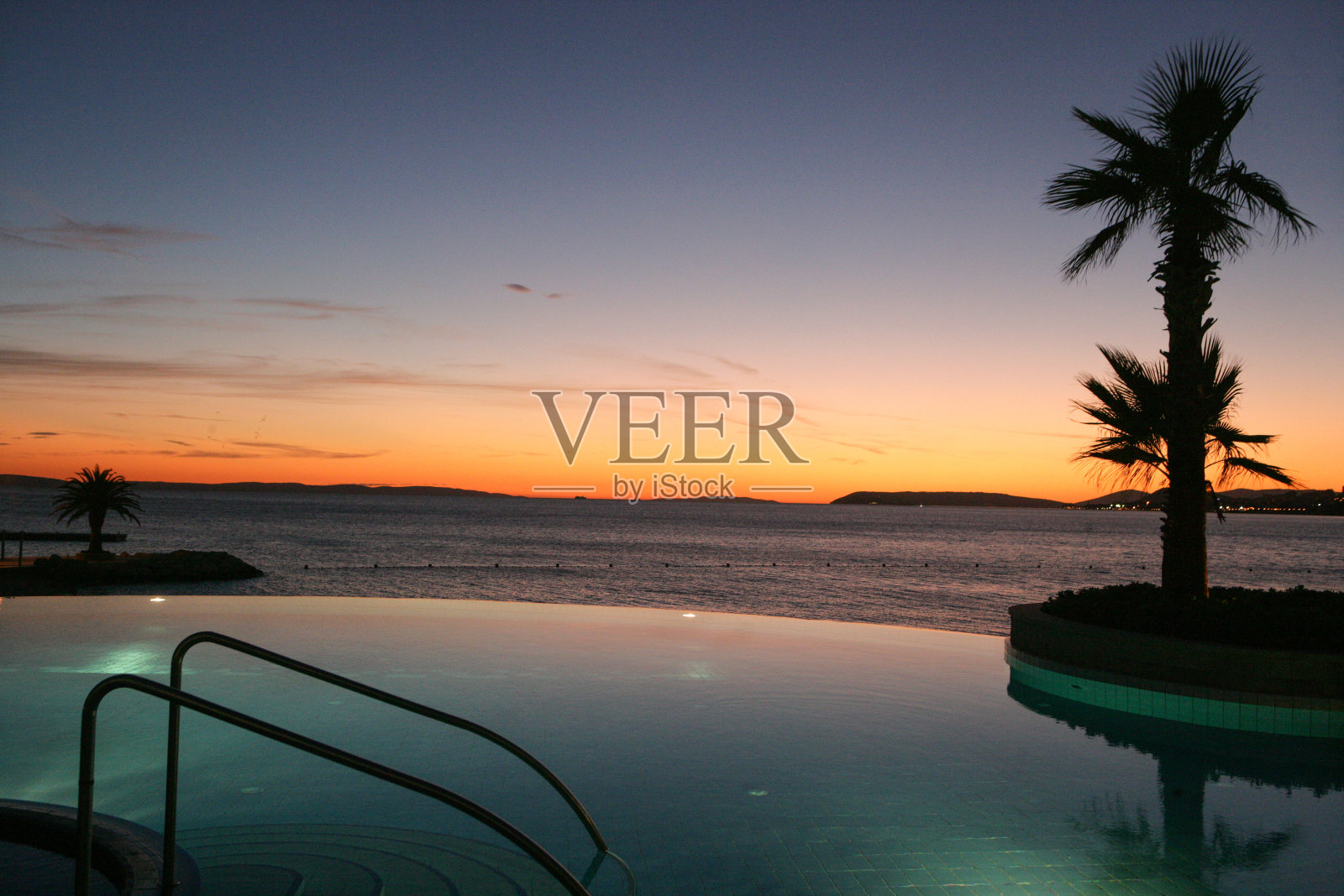 一个游泳池和一个棕榈与大海和日落的背景照片摄影图片