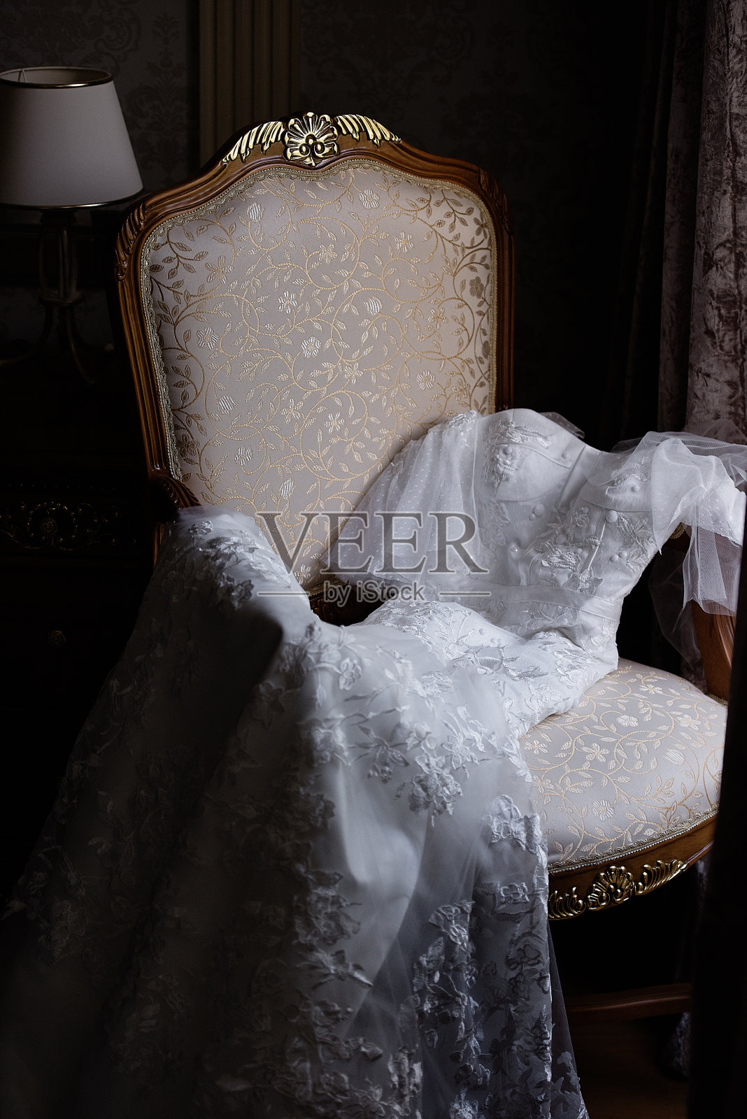 白色纹理的婚纱躺在窗边的椅子上，新娘的费用，婚礼前的早上照片摄影图片